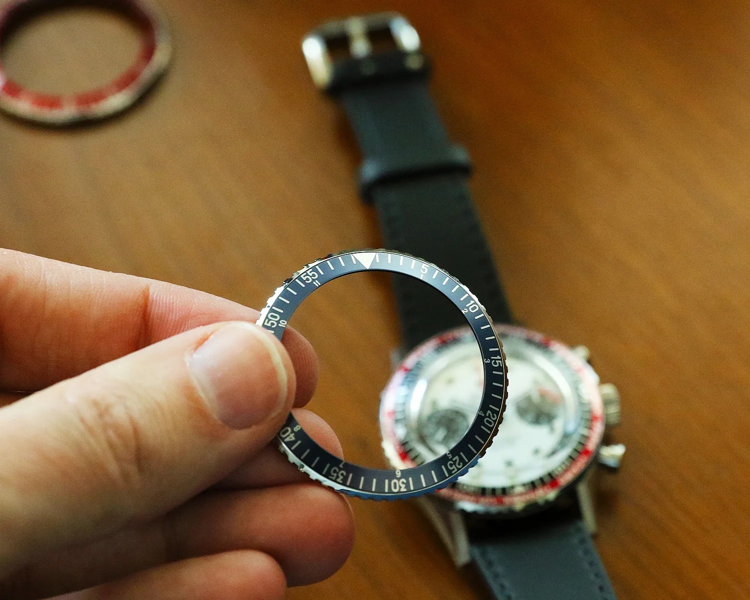 a hand holds a bezel above a nivada chronograph watch