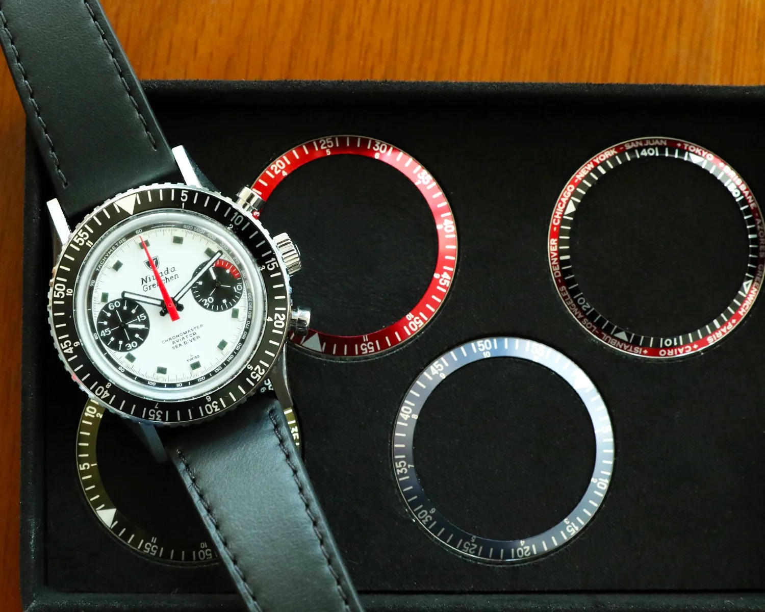 a nivada grenchen chronograph watch on a tray of watch bezels