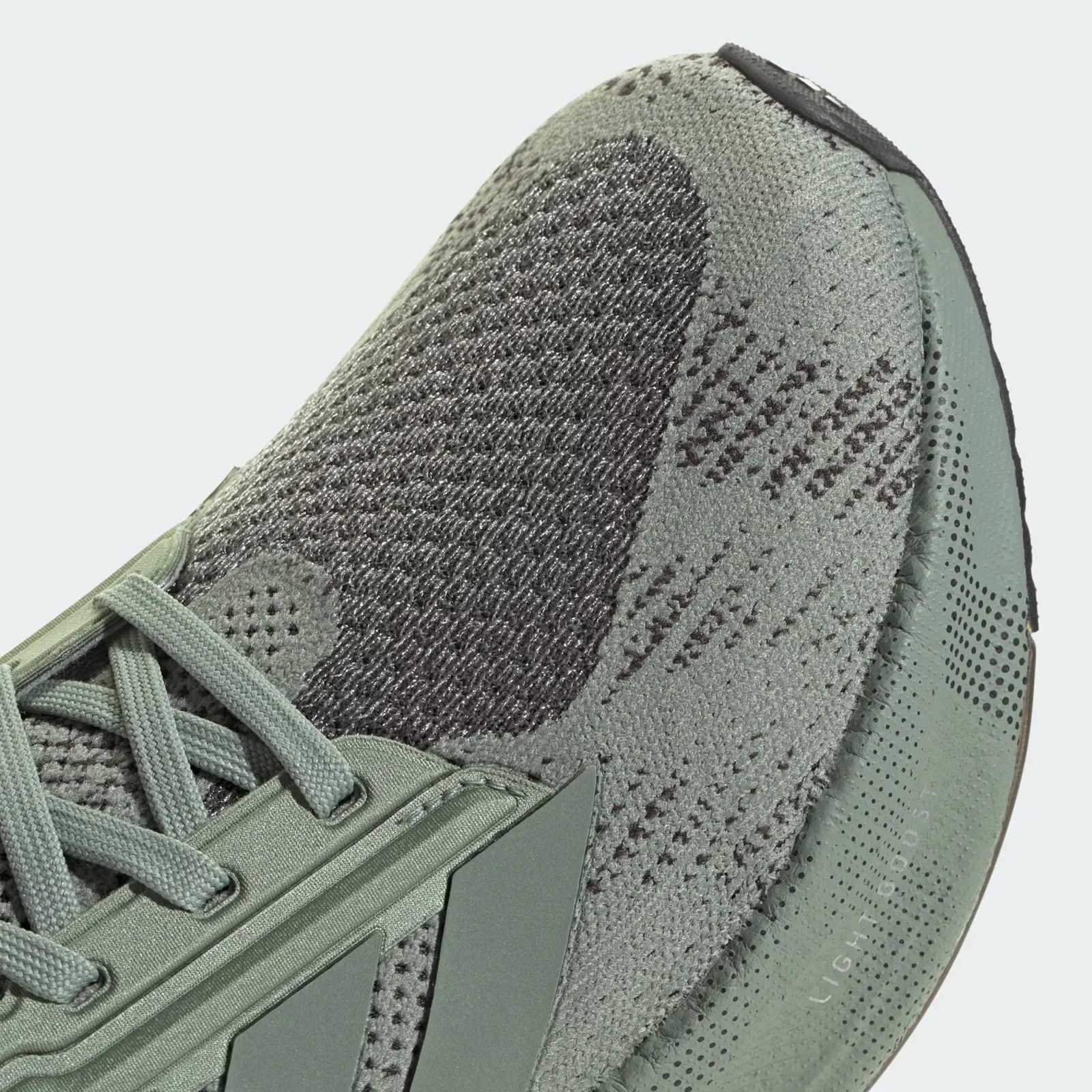 A close up of the upper toe area of an Adidas Ultraboost 5X shoe in silver green up against a light grey background. 