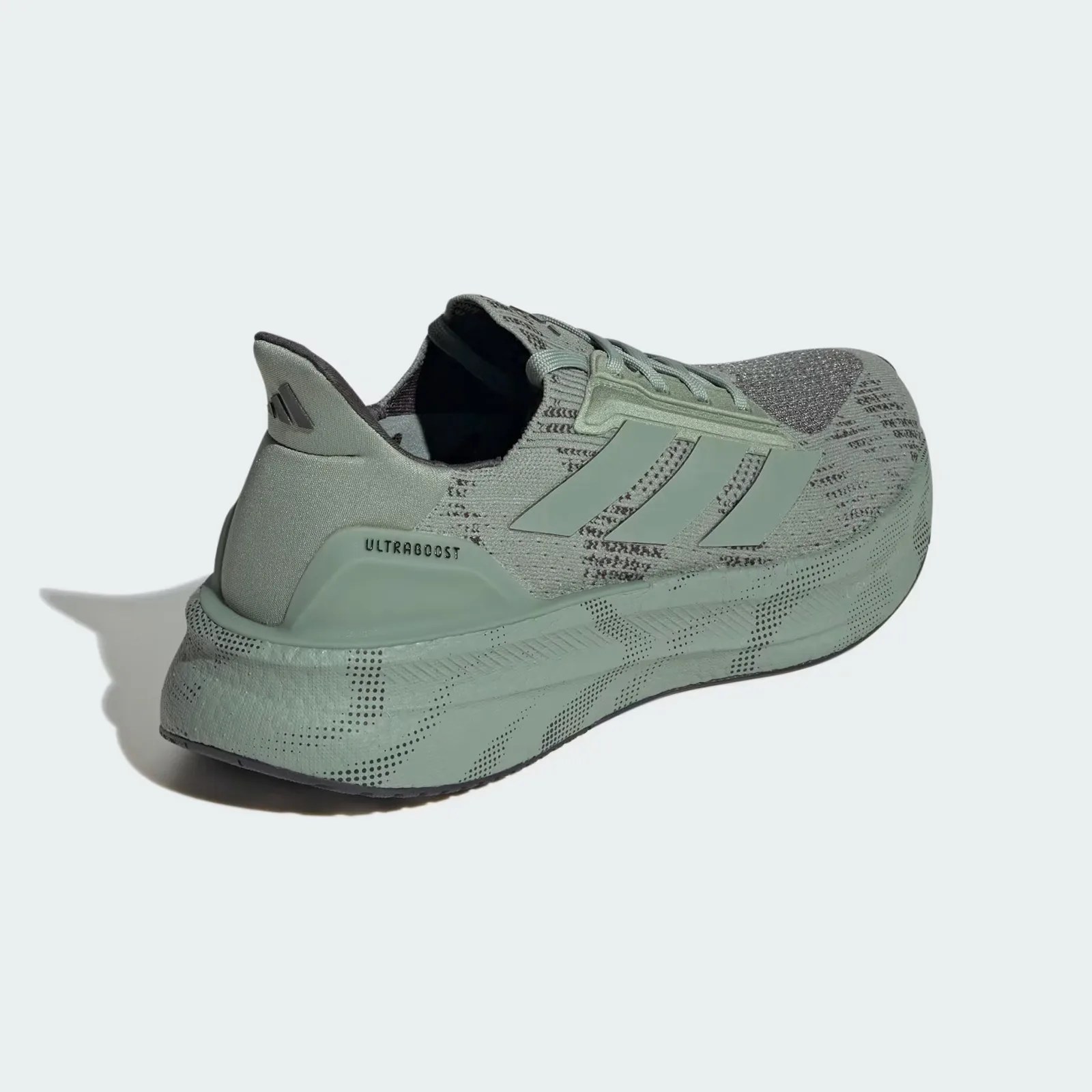 A close up of the heel area of an Adidas Ultraboost 5X shoe in silver green up against a light grey background. 