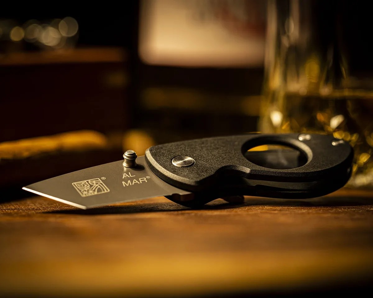 Al Mar Havana Clipper Cigar Cutter on a wood tabletop with blurry background