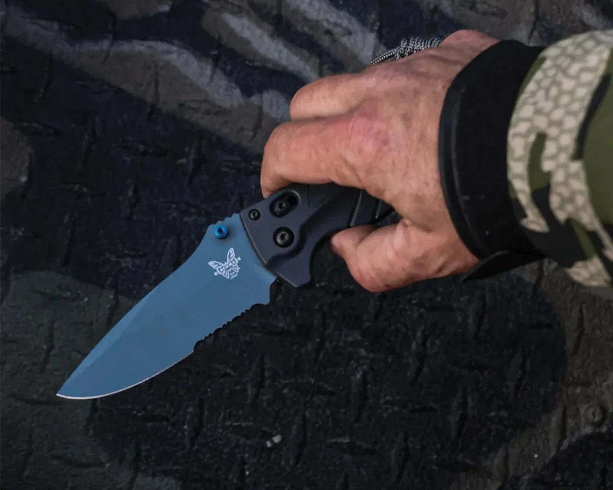 Benchmade Adira knife in man's hand above black metal background