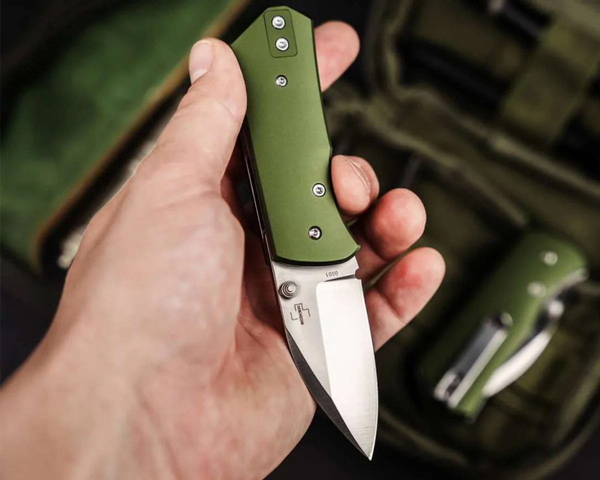 Böker Plus Lefti knife in hand above green blurry background
