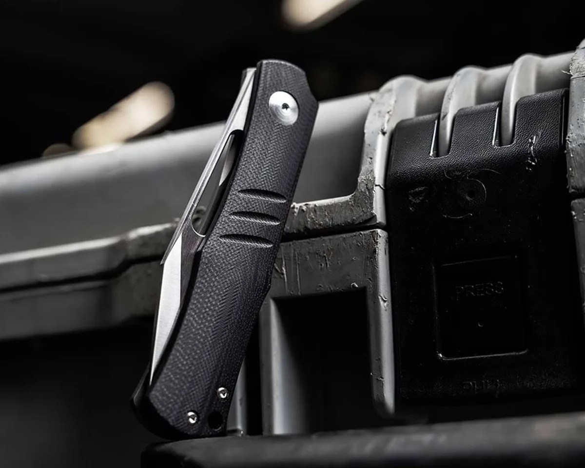 Closed Böker Sliplock knife leaning against rugged carry case