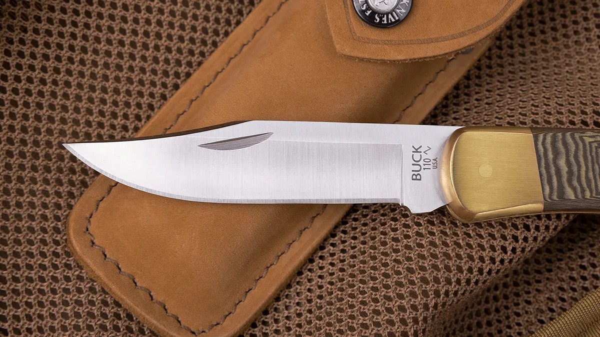 Closeup of blade of Buck 110 Folding Hunter knife on tan mesh bag