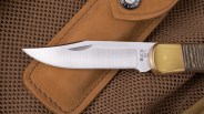 Closeup of blade of Buck 110 Folding Hunter knife on tan mesh bag