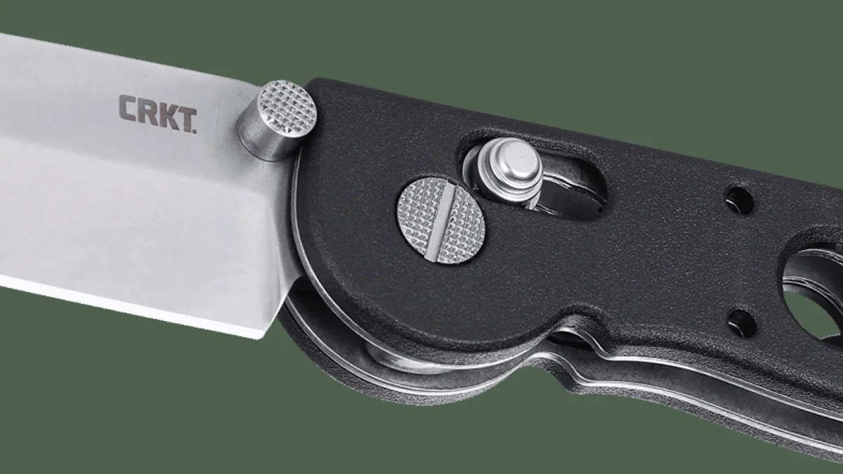 Closeup of CRKT M16 Crossbar knife pivot on green background