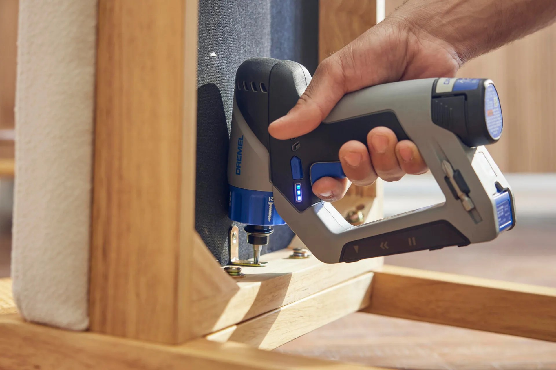 The Dremel Blueprint Multi-Drill shown drilling into a piece of wood into the floor. 