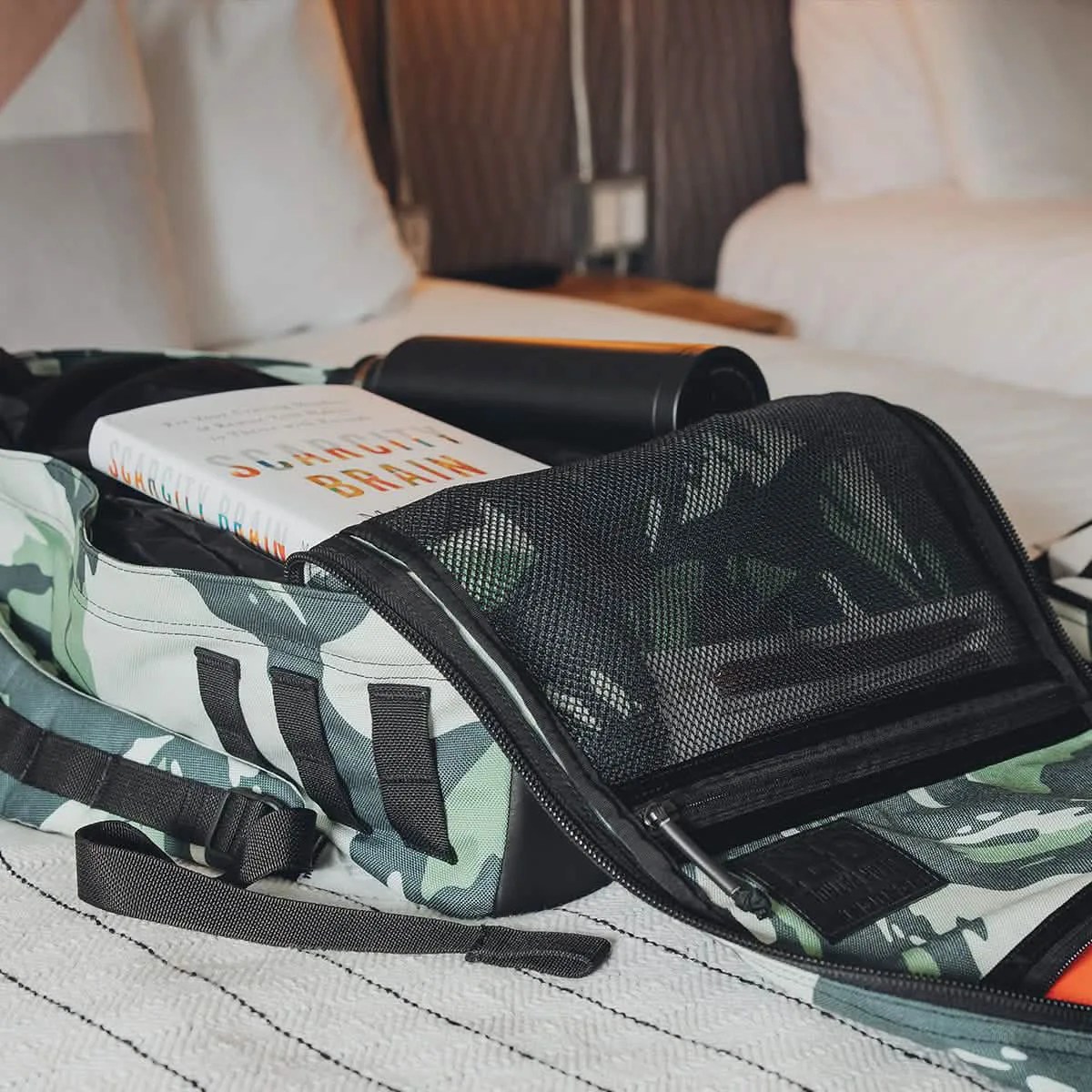 The GoRuck GR1 x Gear Patrol collaborative edition shown fully open laying on a bed to reveal the bag's filled interior pockets and main compartment. 