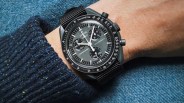Image of the Swatch MoonSwatch Mission to Mercury shown on a wrist against a speckled dark blue sweat on top of a light blue fabric background.