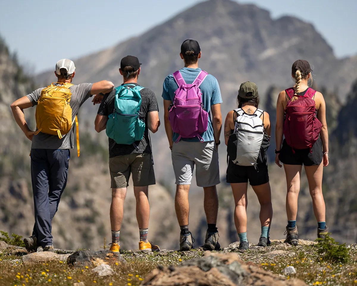 Group of five people on hiking trail wearing Mystery Ranch In and Out Backpacks