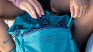 Closeup of person putting sunglasses into Mystery Ranch In and Out Backpack