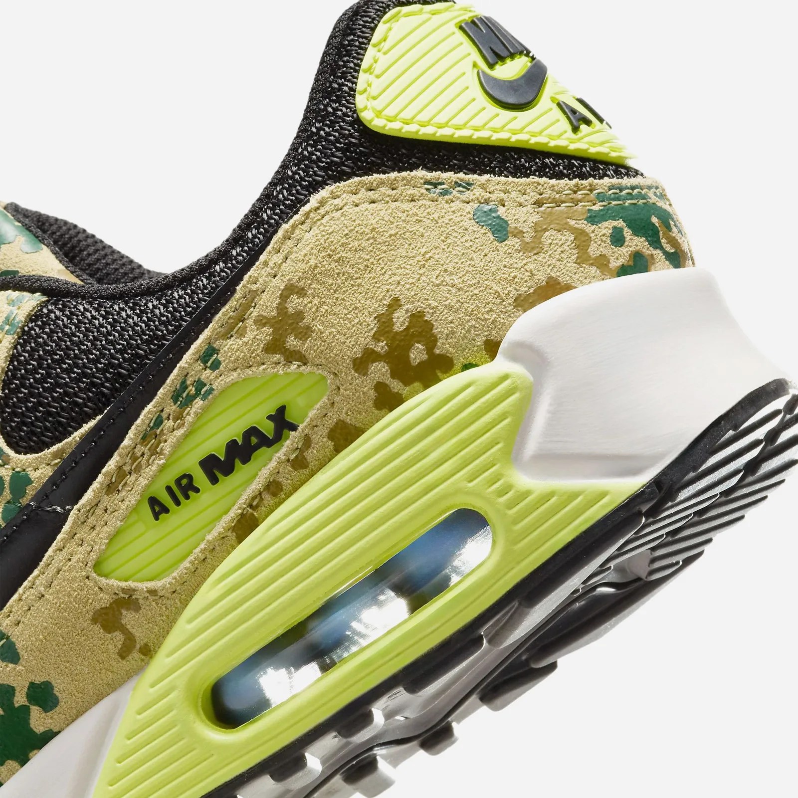 A close up of the heel of the Nike Air Max 90 in "Light Lemon Twist" on a gray background
