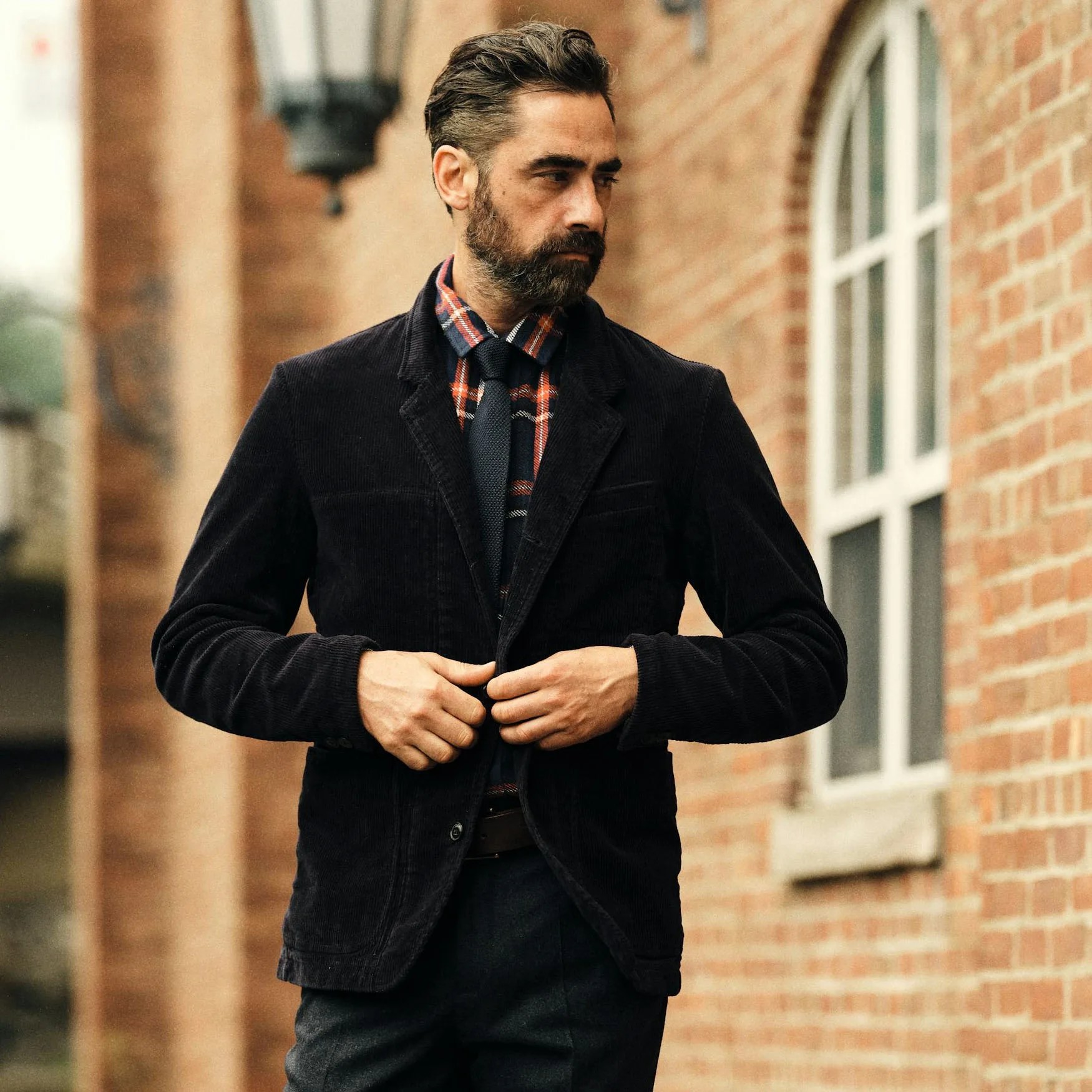 a man buttoning up his corduroy blazer
