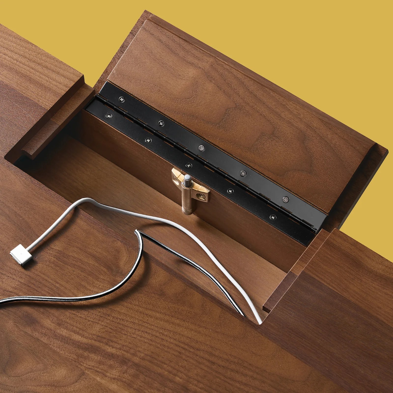 A close up of the surge protector hatch shown open embedded inside Room&Board's Lincoln standing desk