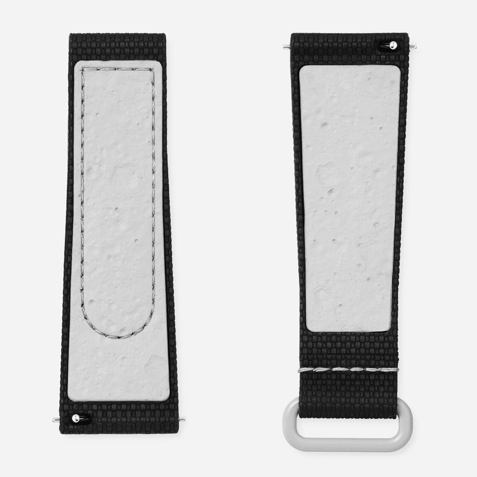 The two pieces of the official Swatch MoonSwatch rubber watch strap shown separated side-by-side against a light grey background. Each strap is shown backwards to reveal the special texture Swatch included that resembles the cratered lunar surface. The strap shown is black, with the lunar surfacing backing in white. 