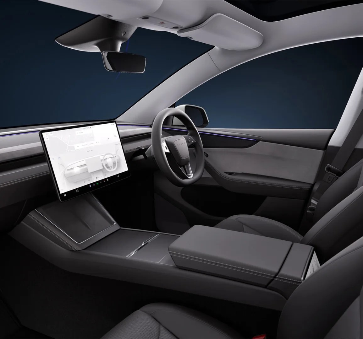 An interior shot of the new 2025 Tesla Model Y showing the front dashboard as viewed from the front passenger side in a right hand drive configuration. The interior screen is lit to highlight the dark grey interior. 
