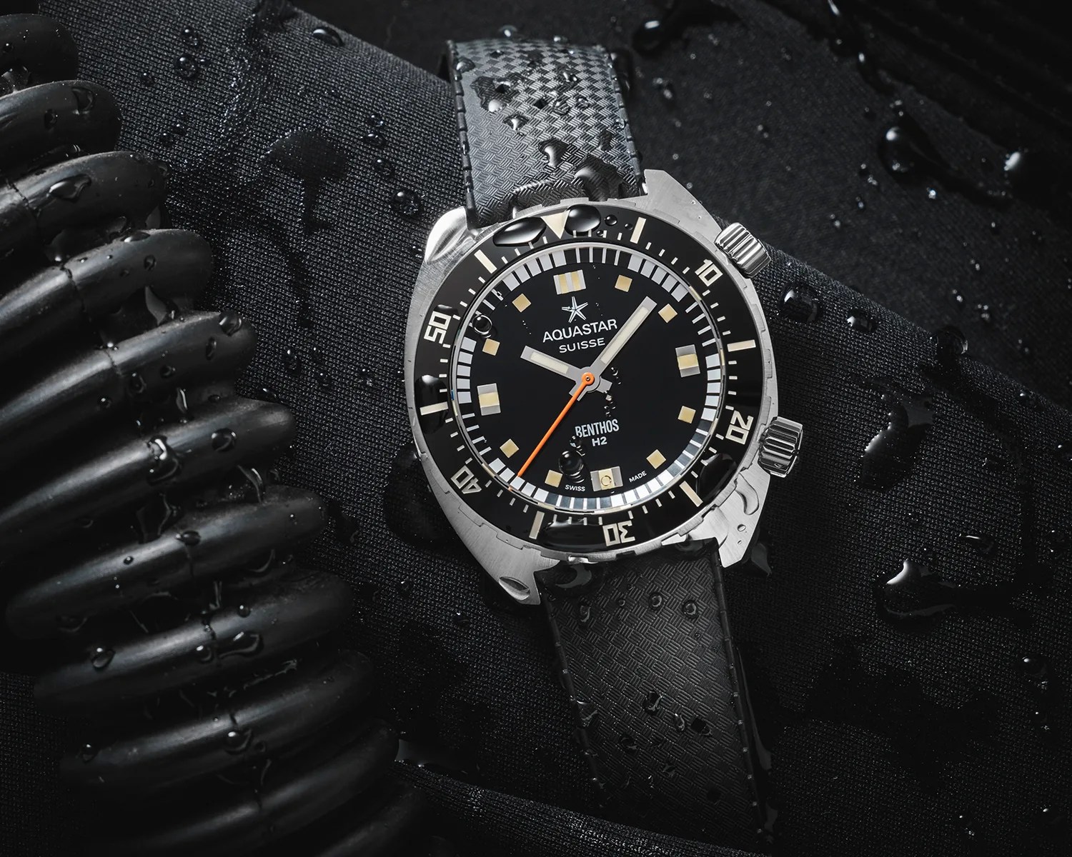 an aquastar dive watch next to some wet diving equipment
