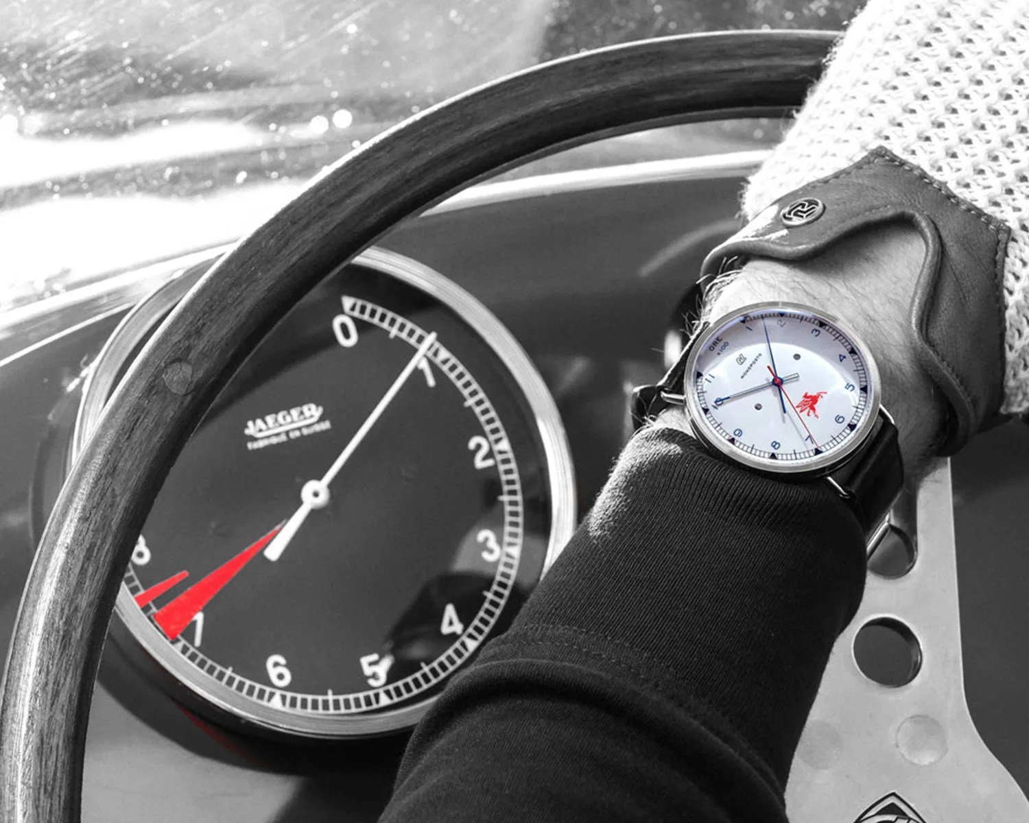 a man wears an autodromo watch while driving an old race car