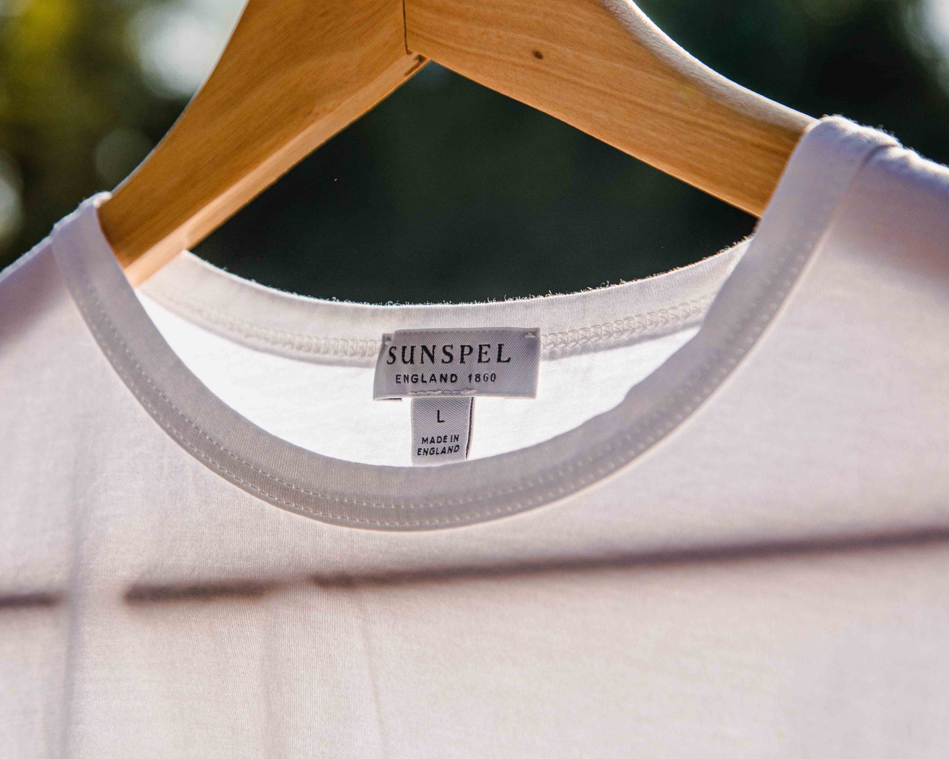 close up of a white t-shirt on a wood hanger