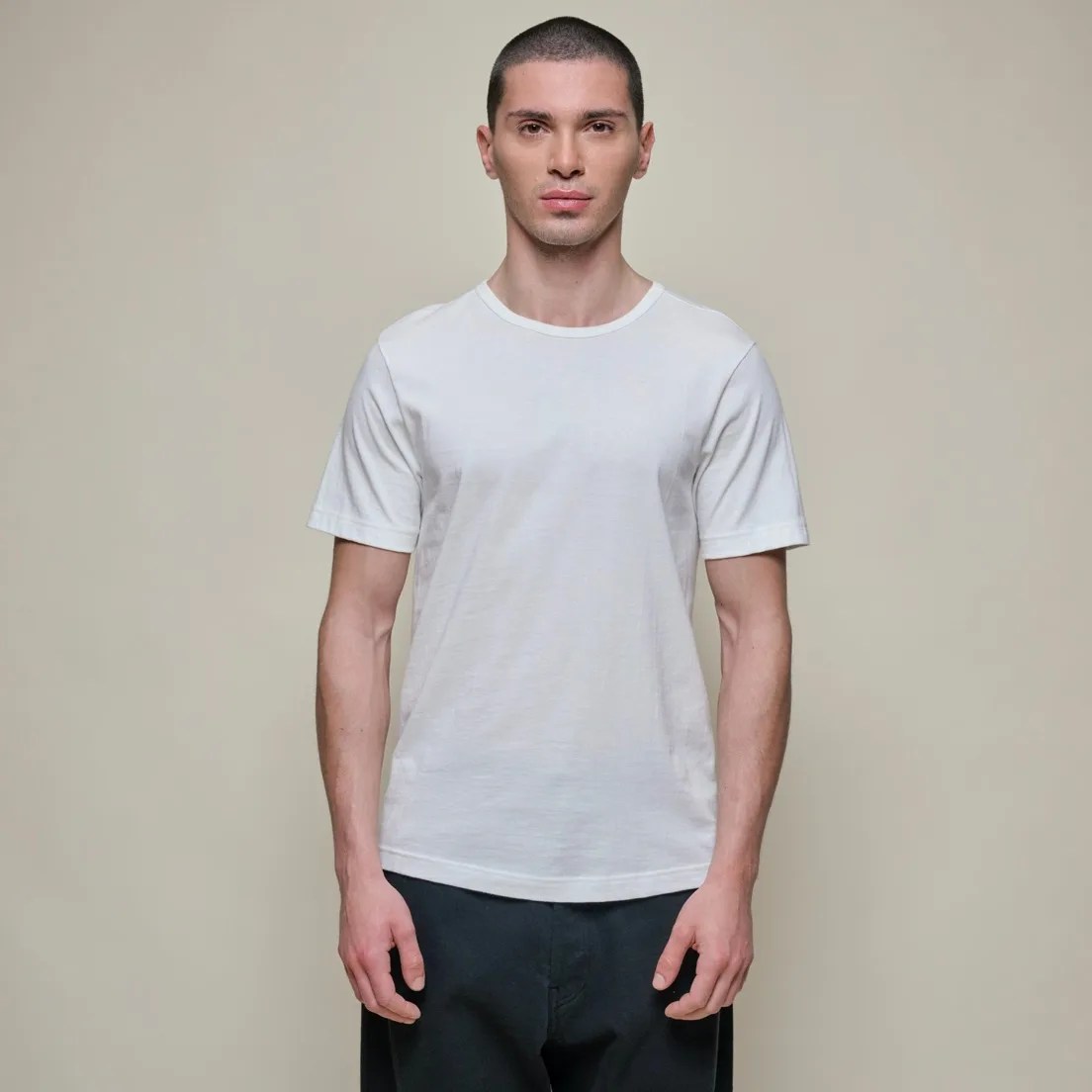 A man wearing a white t-shirt and navy blue chinos