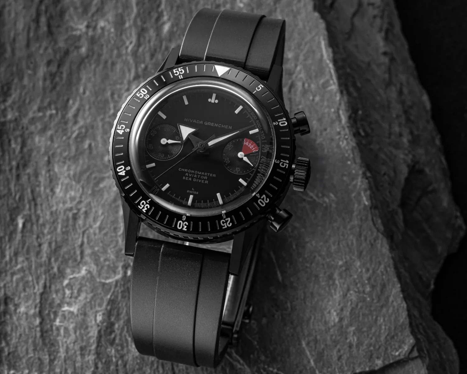 a black nivada grenchen watch on a rock
