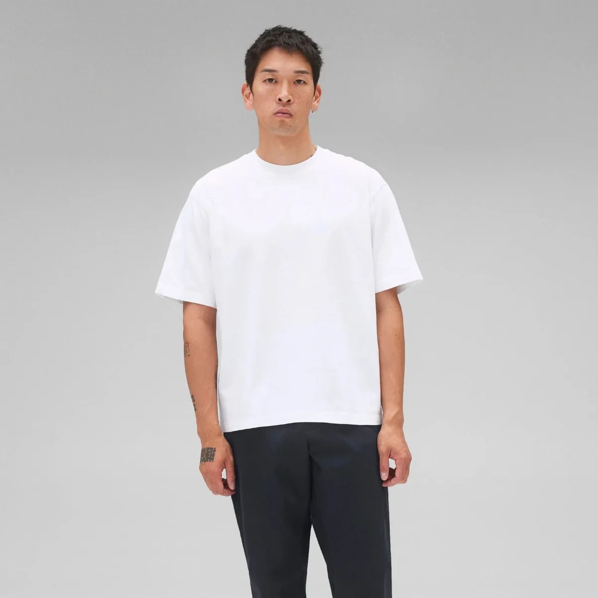 A man wearing a white t-shirt and navy blue chinos
