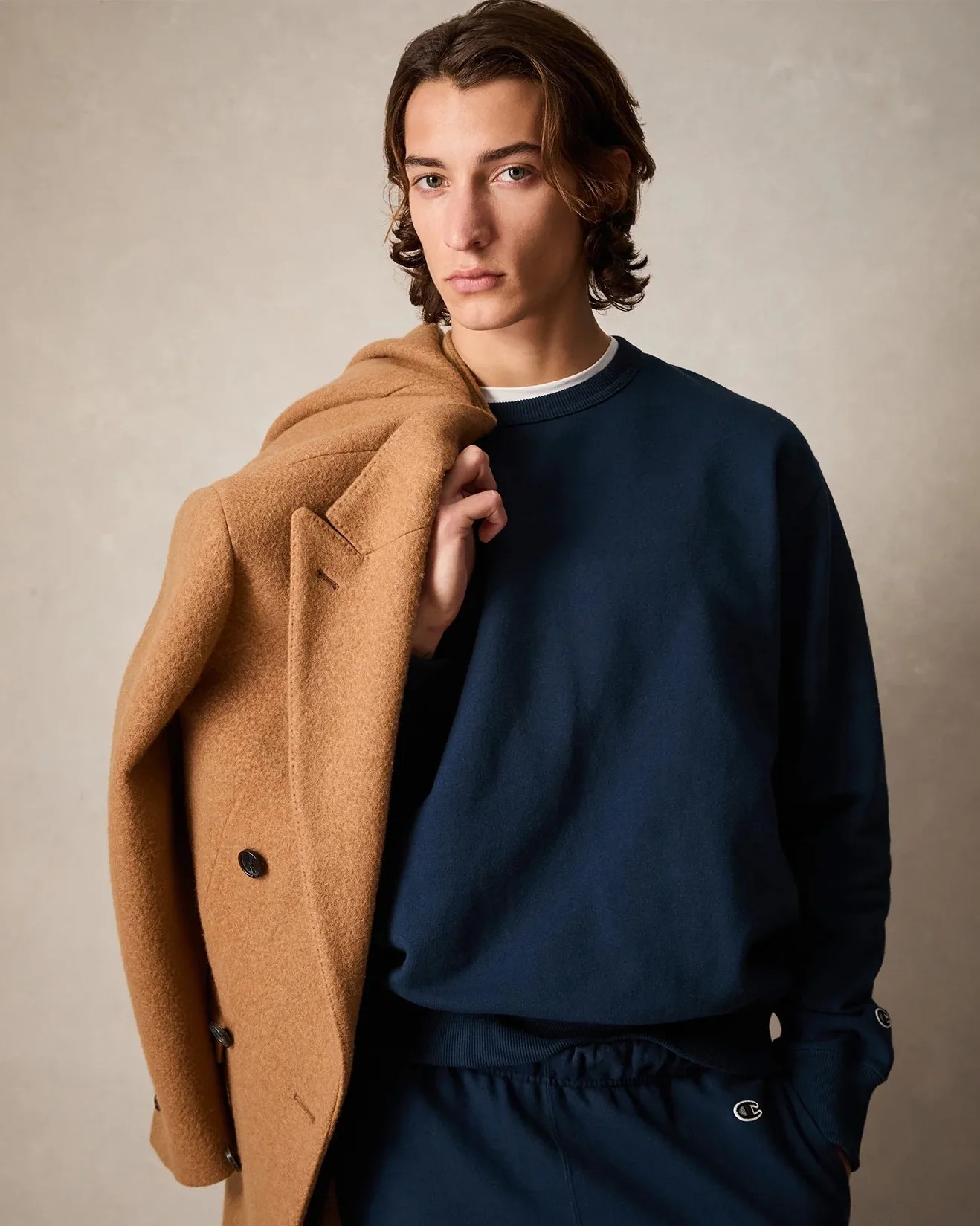 a man wearing a blue sweatshirt and sweatpants holding a jacket