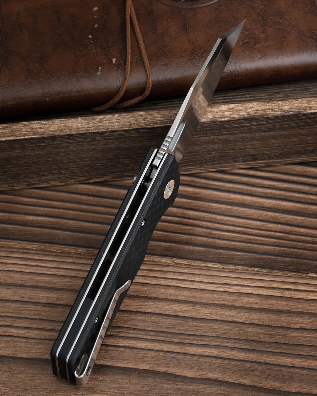 Spine of Bestechman Guardian knife on wood table with leather journal