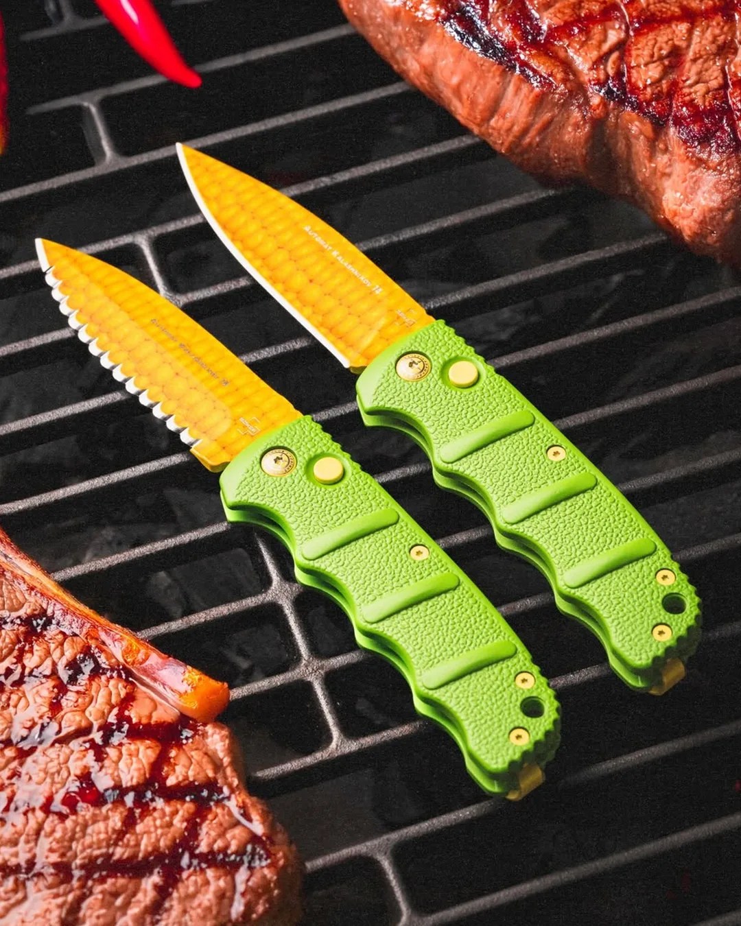 Two Böker KalashniCob knives on BBQ grate next to steaks