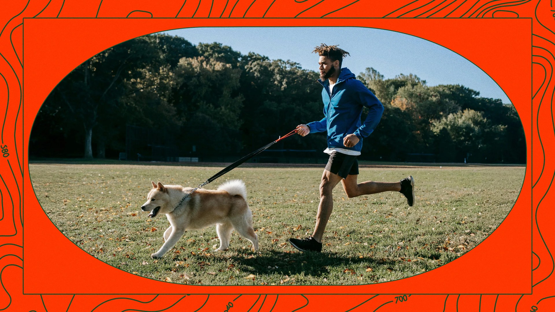 man running with leashed dog on a grassy field