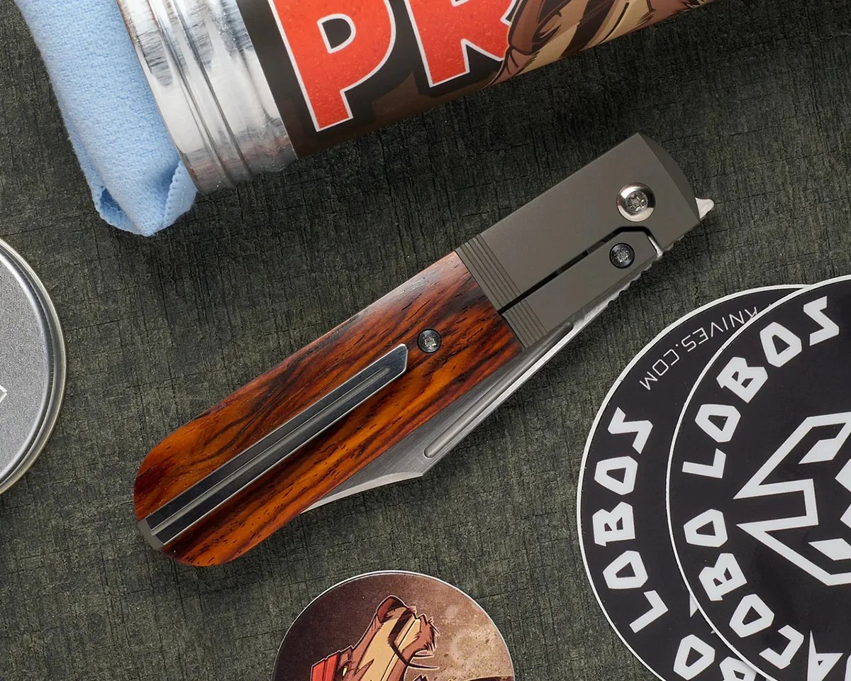 Jack Wolf Knives Primo Jack knife closed on greenish background next to stickers and aluminum tin