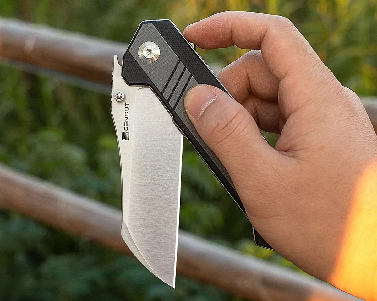Sencut Draxor knife in hand in front of outdoor background