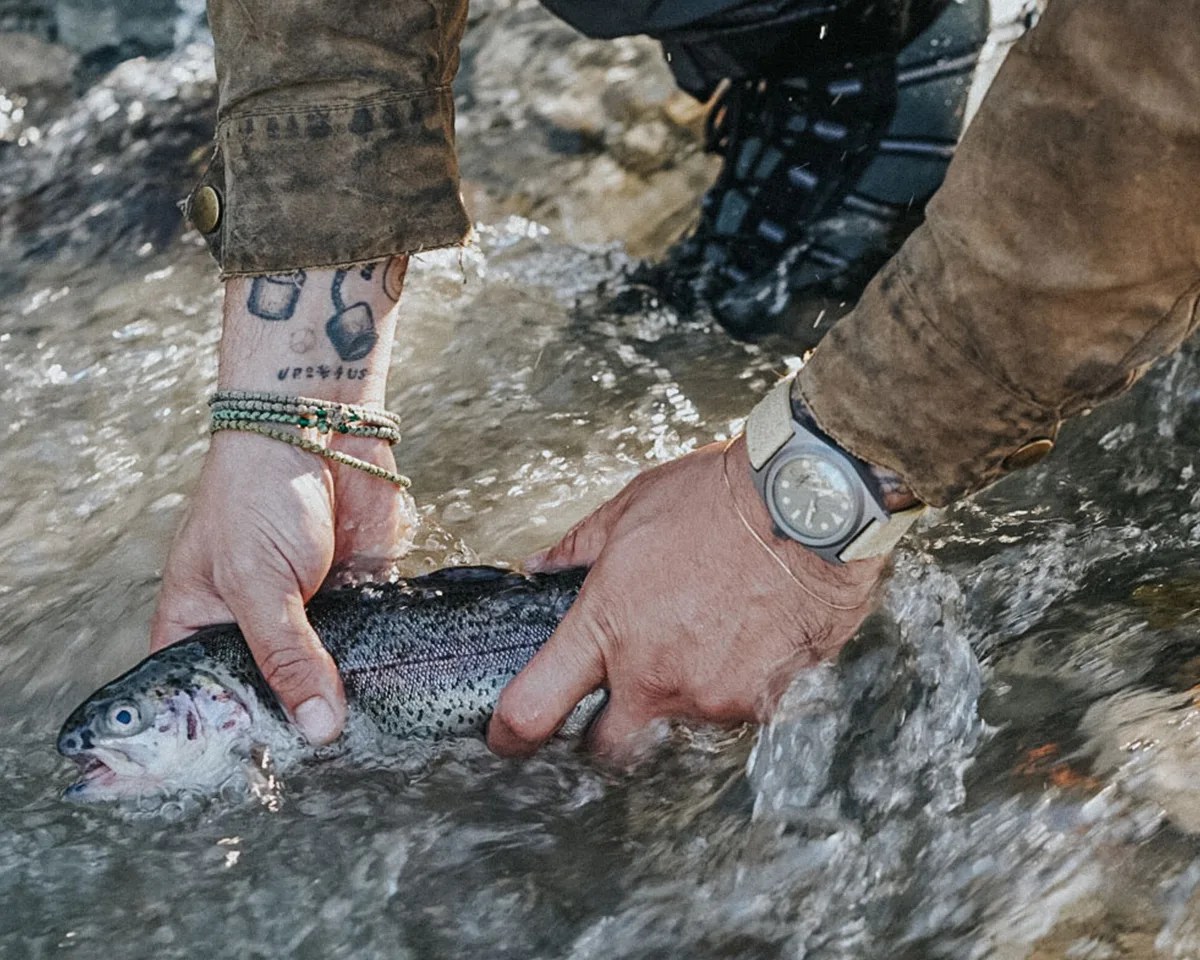 Man grabbing fish from river wearing Unimatic Modello Due U2S T W Field Watch