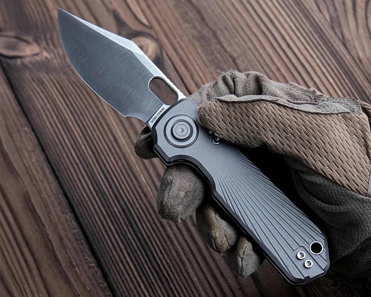Vosteed Akita Knife in gloved hand above wood table
