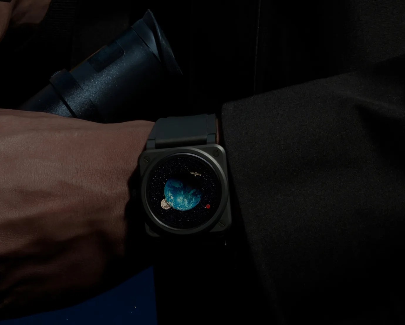 a watch with earth on the dial on a man's wrist