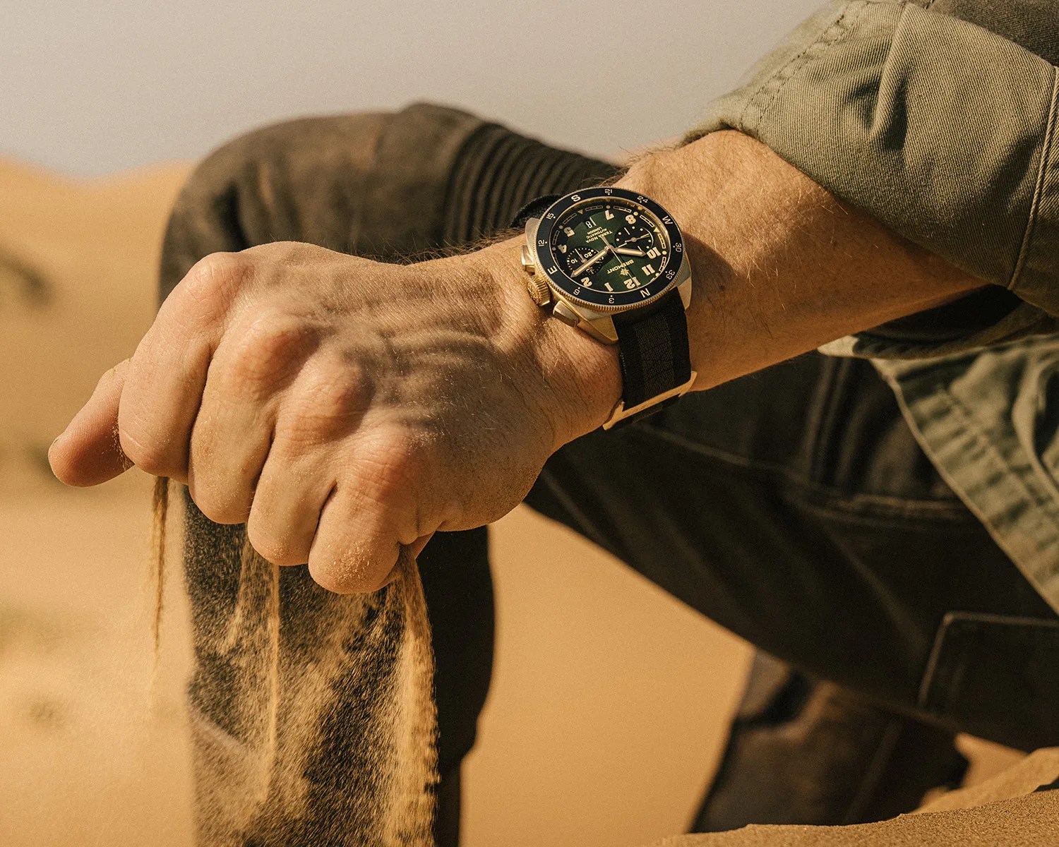 a man plays with sand while wearing a bremont bronze watch
