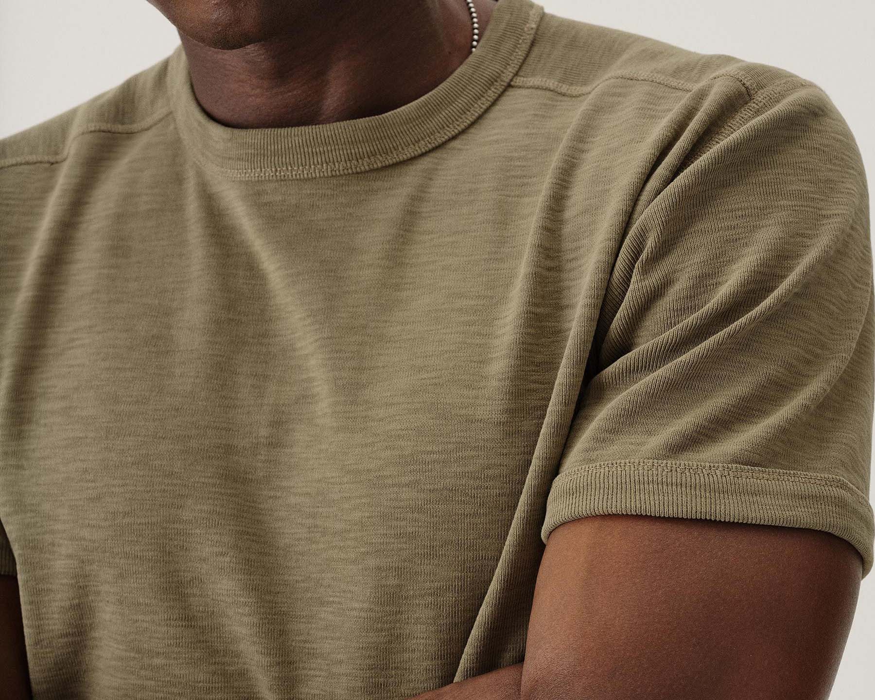 close up of the neck and arm of a green buck mason t-shirt