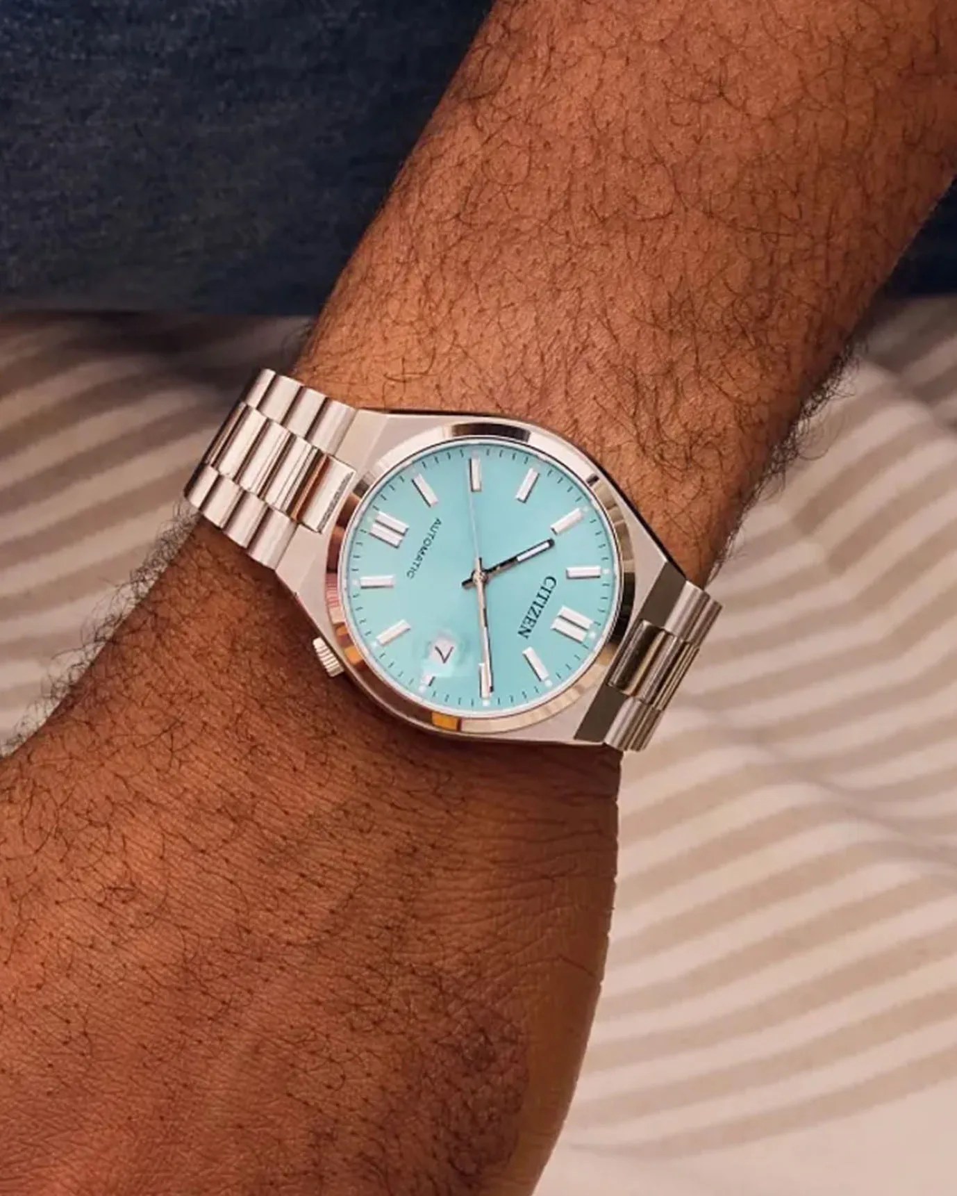 a steel watch with a blue face on a man's wrist
