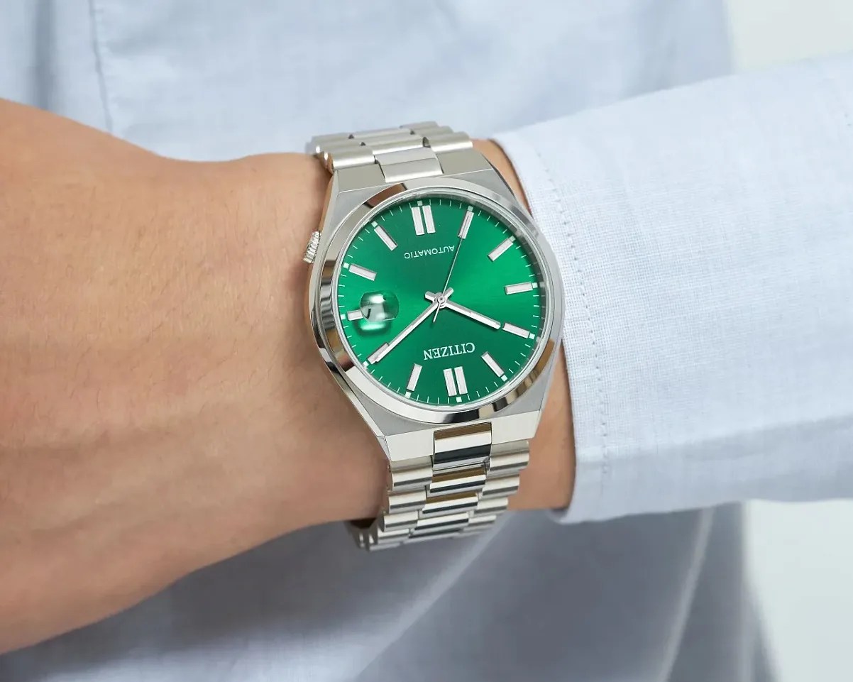 a steel watch with a green dial on a man's wrist