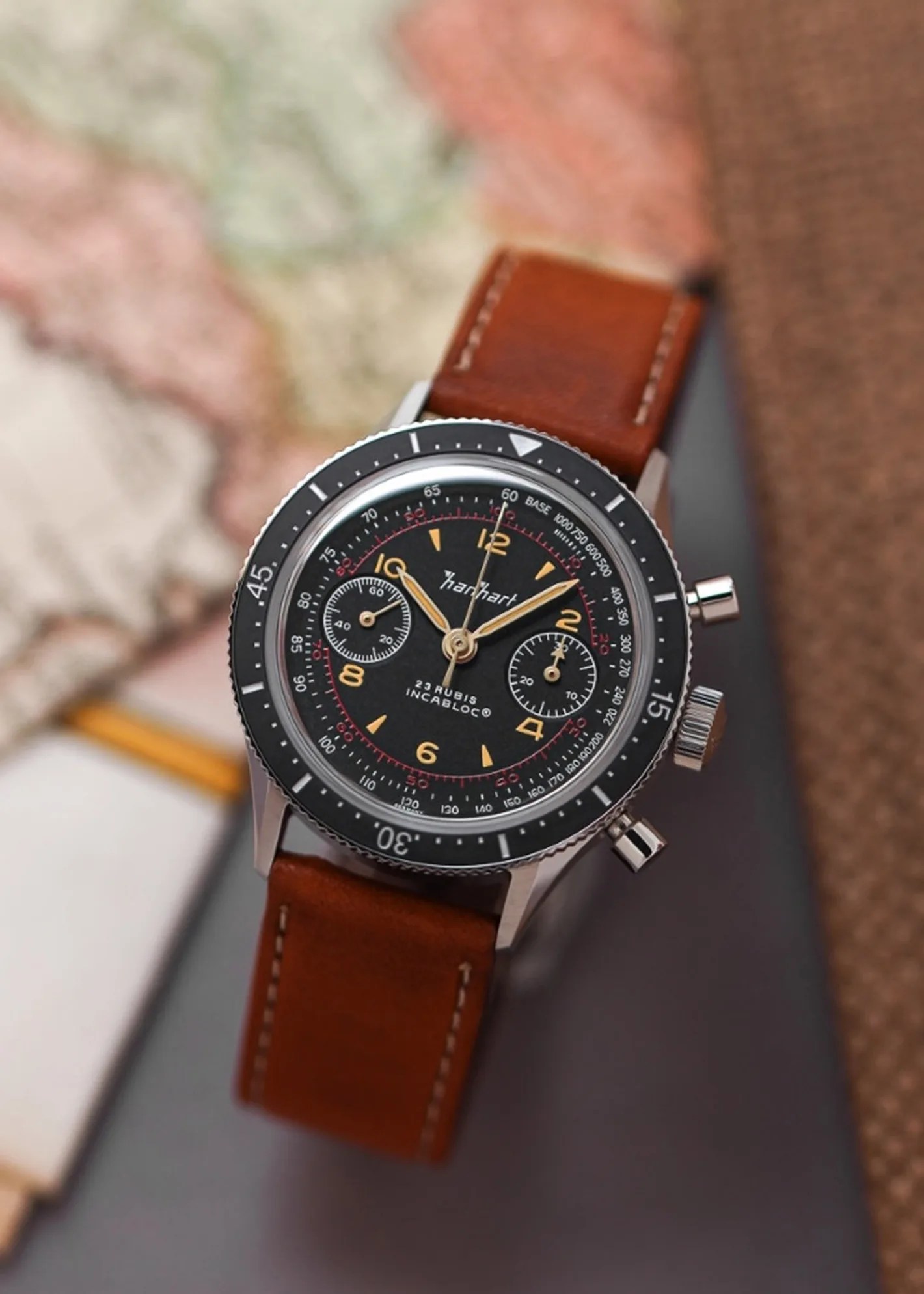 a black chronograph watch with a brown strap