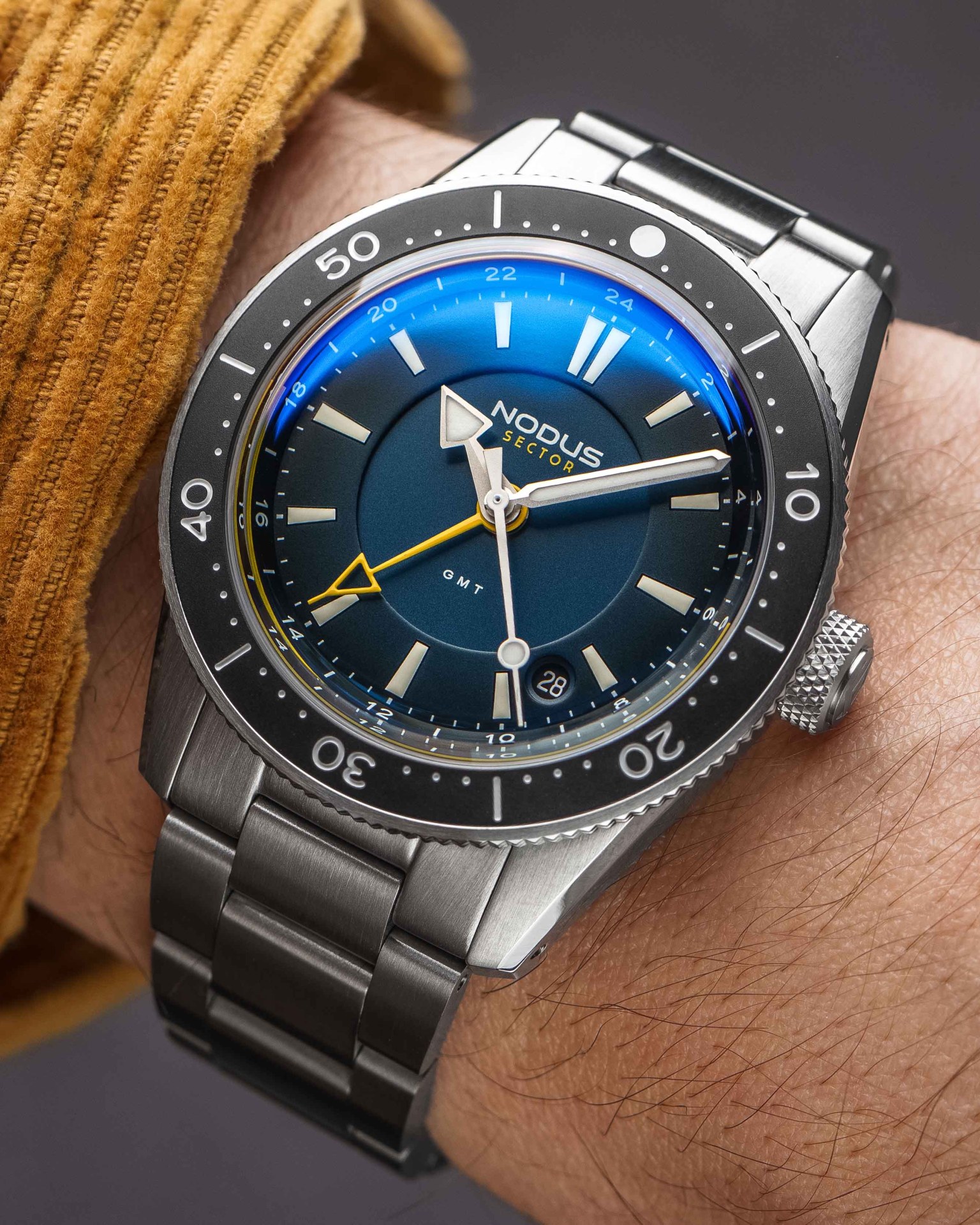 a steel dive watch with a blue dial on a man's wrist