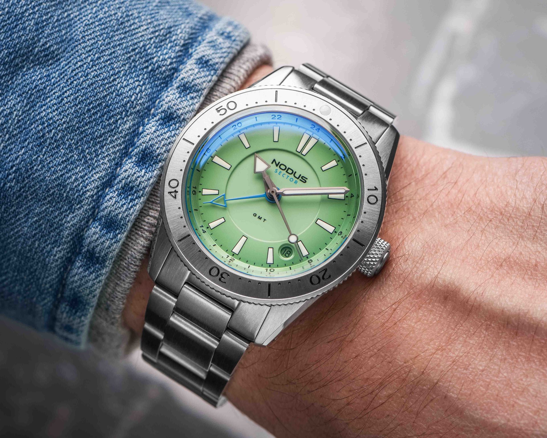 a steel dive watch with a green dial on a man's wrist