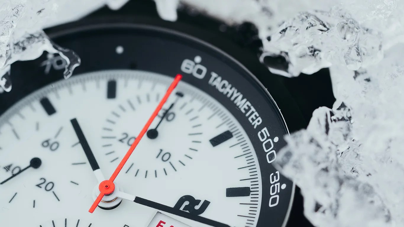 a closeup of a porsche design chronograph watch dial in the snow