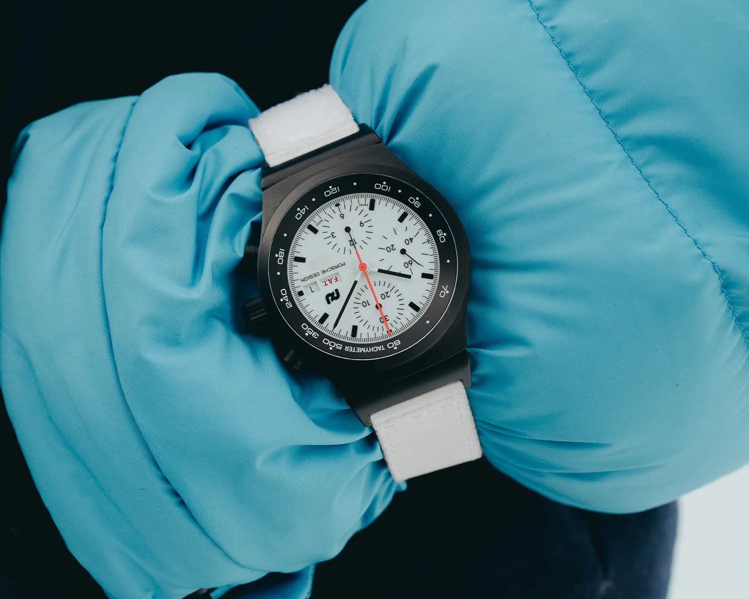a porsche design chronograph watch on a persons wrist over a winter coat