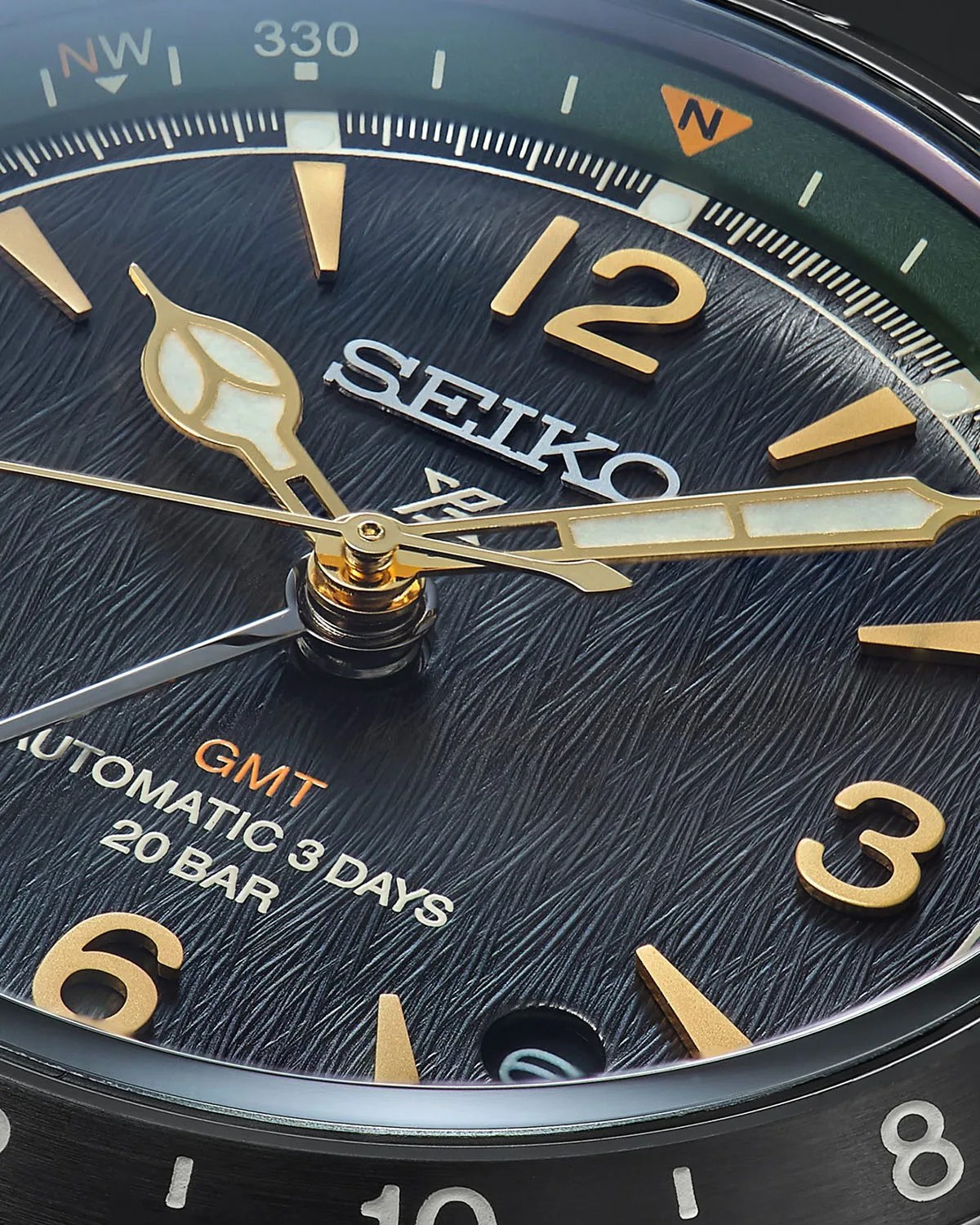 the textured black dial and gold hands of a seiko gmt watch