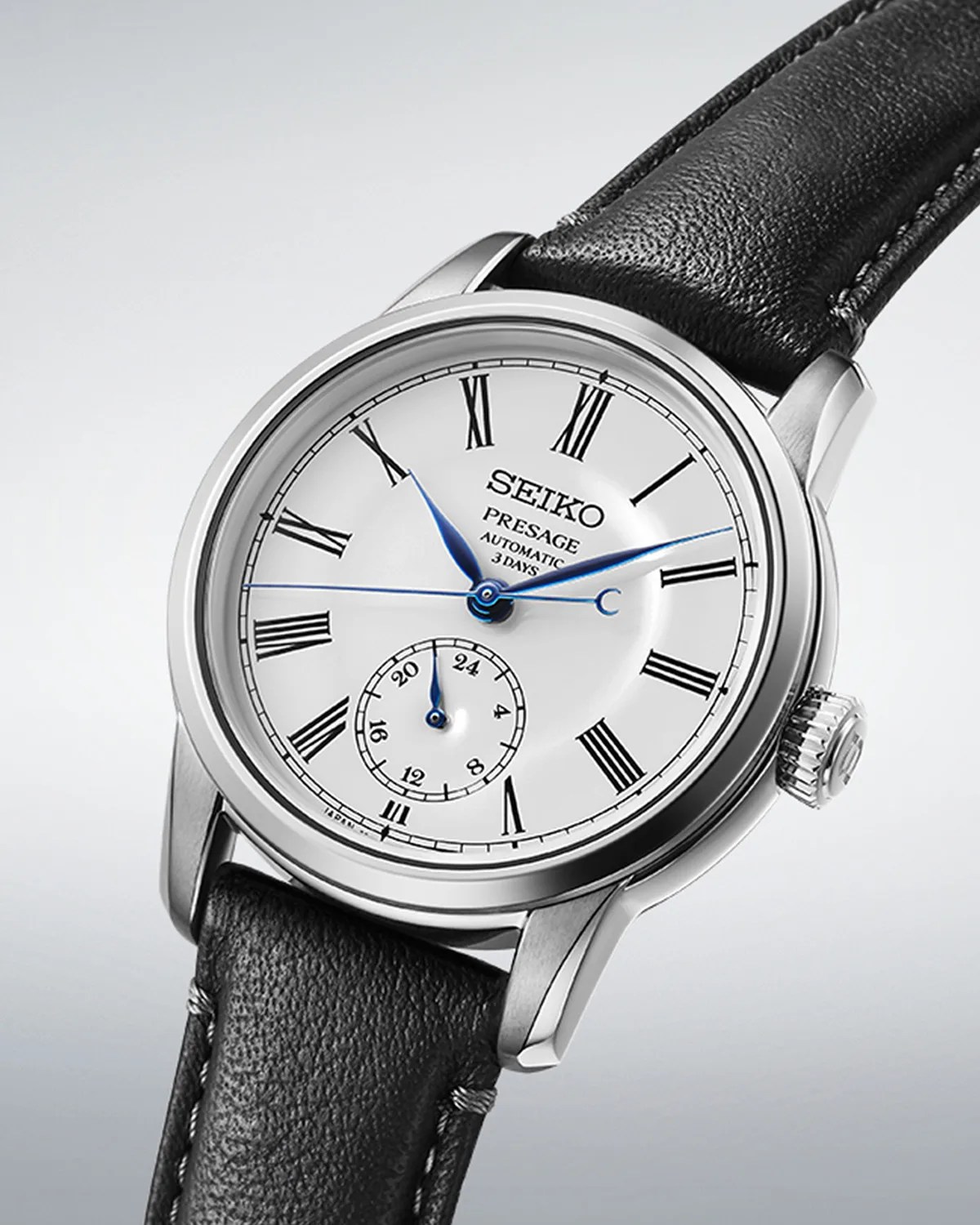 a silver watch with a white dial and black leather band