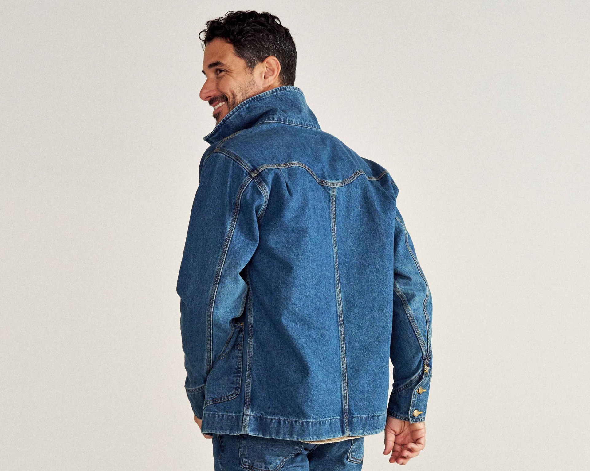 the back of a man wearing a blue denim chore coat