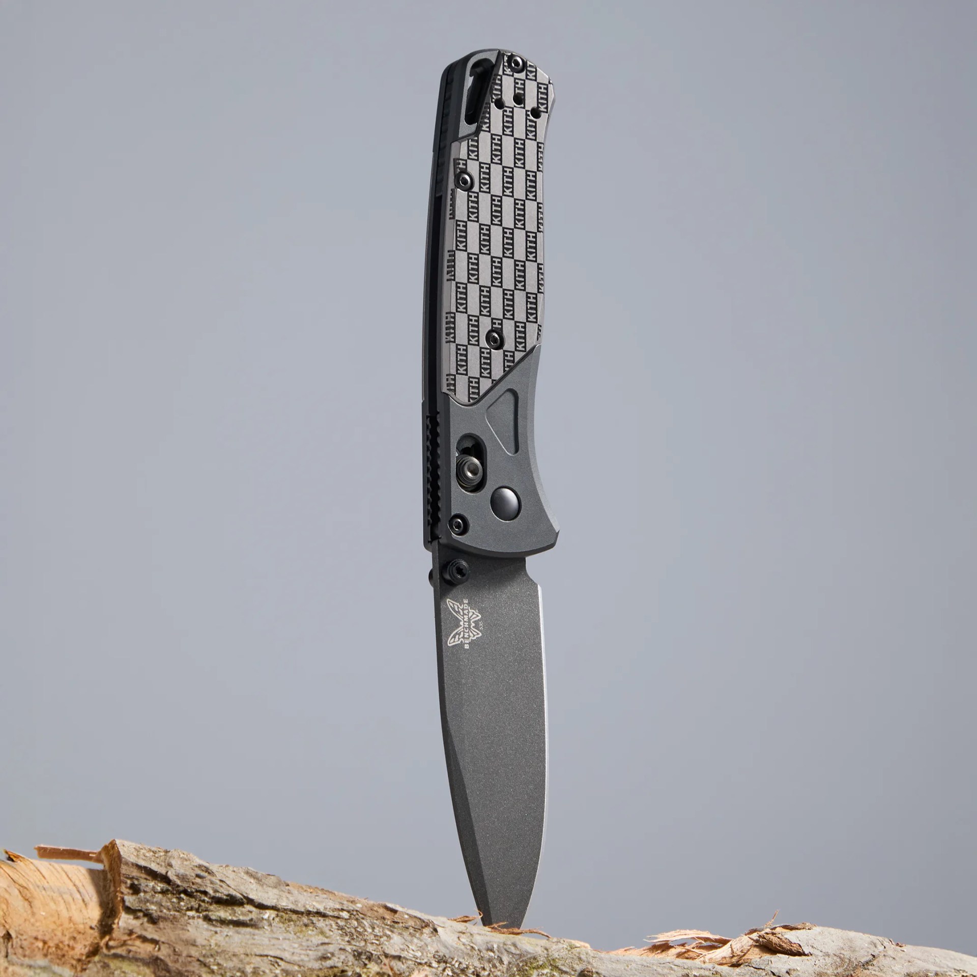 Benchmade BKC x Kith Bugout 535BK 2501 stuck in wood on gray background