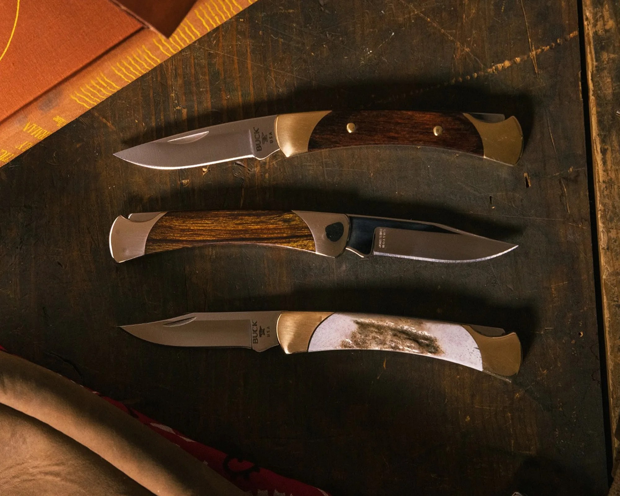A trio of Buck 55 Custom Knives on wood table